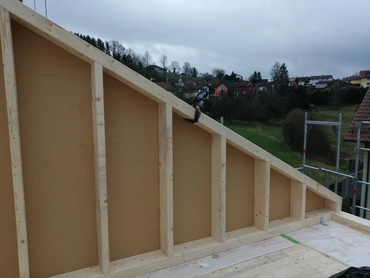 Innenansicht einer Giebelwand im Holzrahmenbau mit Holzfaserdämmplatten und sichtbarer Konstruktion
