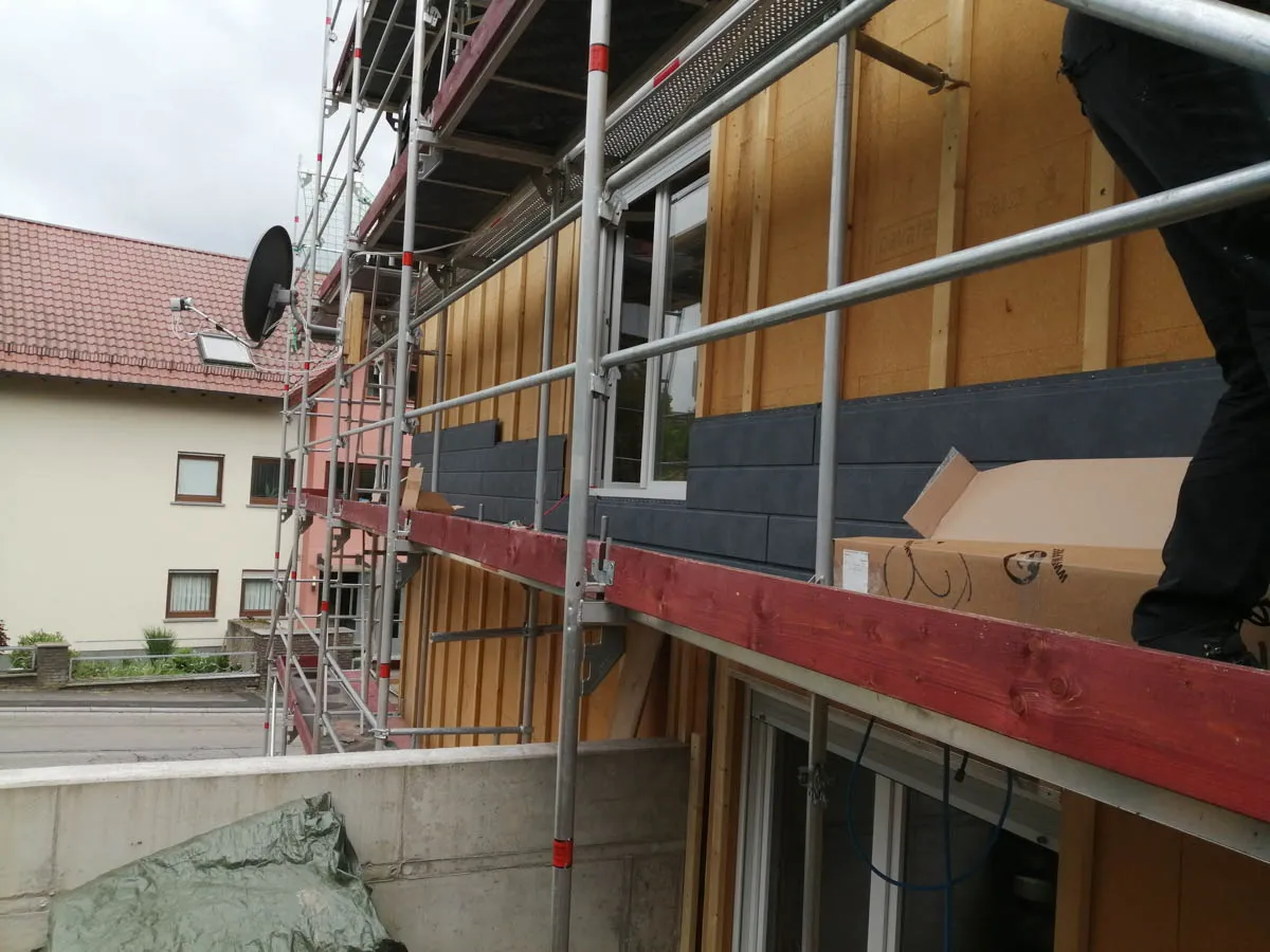 Fassadenunterkonstruktion aus Holz mit Holzfaserdämmung und Gerüst während der energetischen Sanierung