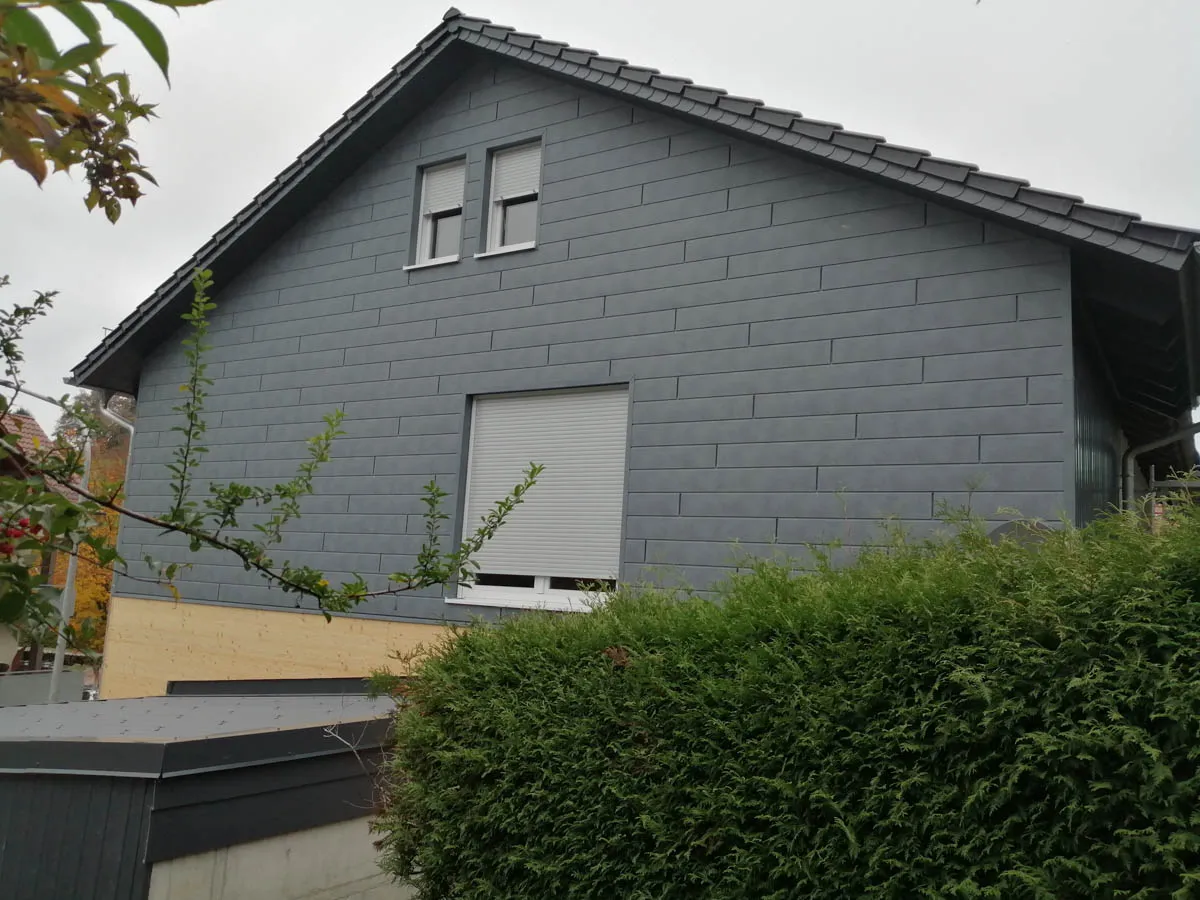 Außenansicht eines sanierten Wohnhauses mit moderner Fassadenverkleidung in Holzbauweise