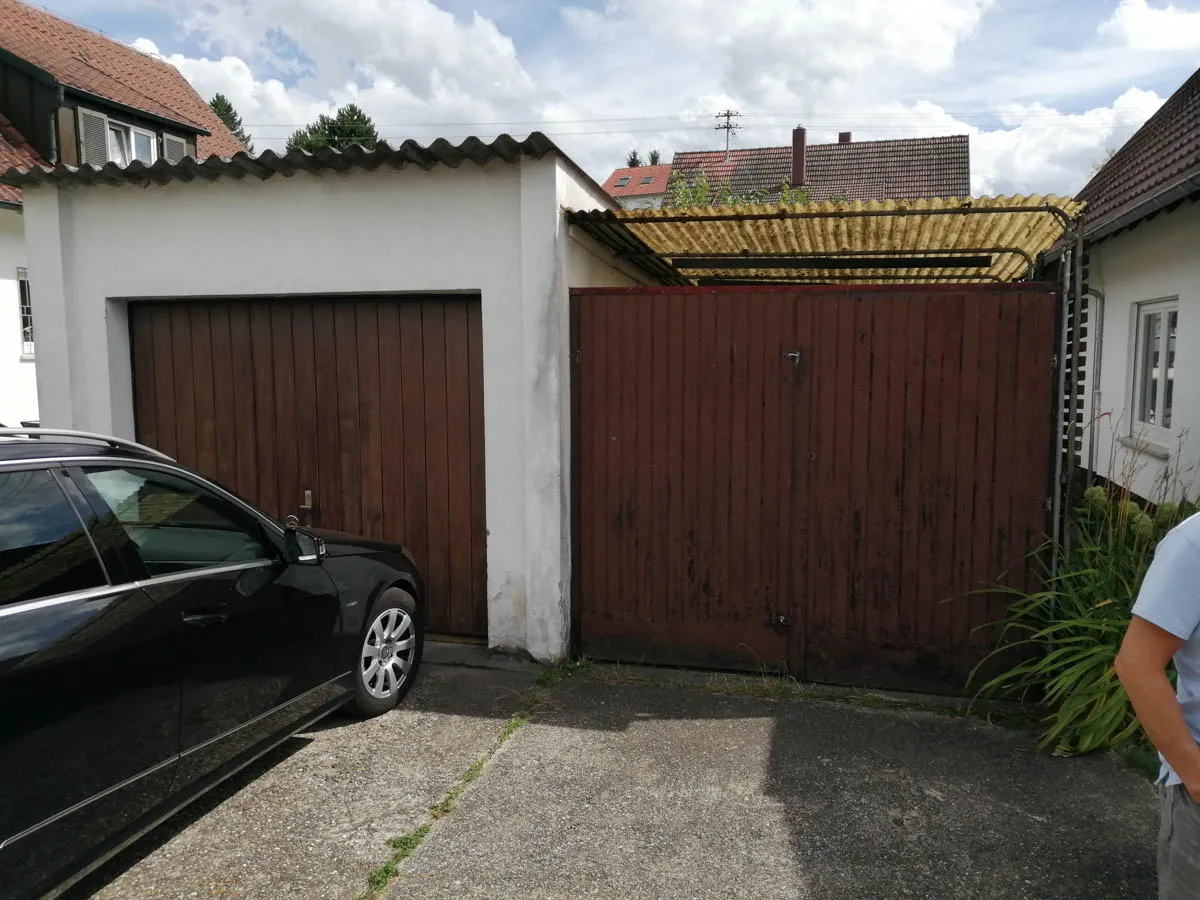 Bestandsgarage mit Holztor vor dem Beginn der Abbruch- und Neubauarbeiten